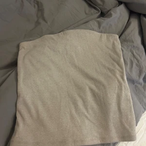 Glittrig beige tubtopp från Stockh LM Studio - Säljer en snygg glittrig beige tubtopp från Stockh LM Studio. Perfekt för att lägga till lite glitter i din outfit. Toppen är ärmlös och har en stilren design. Storlek M, har en slags tråd längst upp som gör att den inte åker ner. Nypris 400kr, mitt pris 200. 