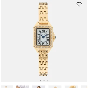 Ivy n rose klocka - Elegant guldfärgad klocka med fyrkantig urtavla och romerska siffror. Urtavlan är omgiven av glittrande strassdetaljer. Armbandet är i metall med en klassisk länkdesign. Perfekt för att lägga till en touch av glamour till din stil.