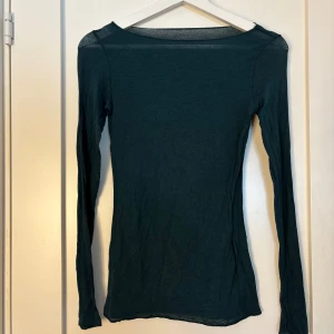 Mörkgrön långärmad topp - Säljer en stilren mörkgrön långärmad topp. Perfekt för lager-på-lager eller som den är. Toppen har en enkel design med rund hals och är tillverkad i ett mjukt material. Kan ha tecken på användning ☺️
