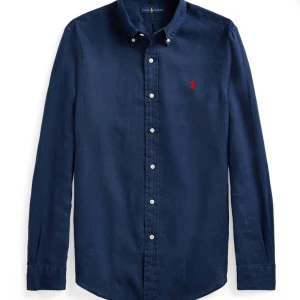 Mörkblå skjorta från Ralph Lauren - Snygg mörkblå skjorta från Ralph Lauren med klassisk krage och broderad logga på bröstet. Skjortan har långa ärmar och knappar framtill. Perfekt för en stilren look.                   Pris kan diskuteras  passar 11-13