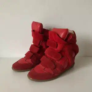 Snygga röda sneakers i mocka med kardborreband. Skorna har en unik design med högre skaft och rundad tå. Perfekta för att ge en färgklick till din outfit. Storlek 42