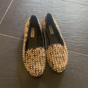 Leopardmönstrade loafers med nitar - Snygga loafers med leopardmönster och guldnitar. Perfekta för att ge en edgy touch till din outfit. Skorna har en platt sula och är lätta att bära. Kanske fattas nån nit men inget jag kan se😁