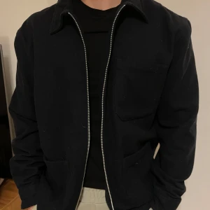 Marinblå jacka från These Glory Days - Säljer en stilren  jacka från These Glory Days. Jackan har en dragkedja framtill och en klassisk krage. Perfekt för en minimalistisk look. Storleken passar allt från en M till XXL. Nypris 1600