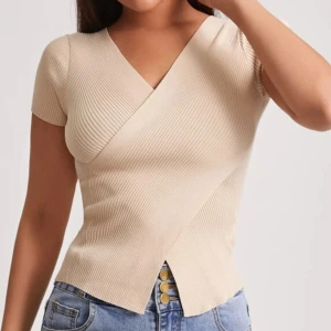 Beige ribbad omlottopp - Snygg beige ribbad omlottopp med korta ärmar och v-ringning. Perfekt för en stilren look, passar bra till jeans eller kjol.