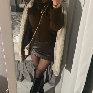 Minikjol - Snygg mörkbrun skinnkjol i kort modell. Perfekt för en trendig look med hög midja och figurnära passform. Kjolen har en stilren design som passar till många olika outfits.