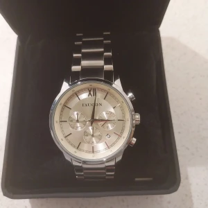 Ny klocka från Faucon - En helt ny klocka från Faucon. Klockan är helt ny och oanvänd, alla lappar är fortfarande kvar på klockan. Den är helt i rostfritt stål och har safirglas, samt ett fint och rejält fjärilslås. Klockan levereras i en lyxig klocklåda. 