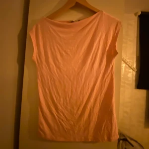 Rosa topp - Säljer en enkel och stilren rosa topp med korta ärmar. Perfekt för en avslappnad look.