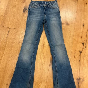 Blå bootcut jeans från ONLY - Snygga blå bootcut jeans. Märkeslapp i brunt läder baktill. Dem har medelhög midja och är lite upptrampade nedtill.