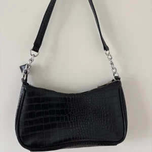 Svart axelväska från Glitter - Snygg svart axelväska i krokodilpräglat mönster från Glitter. Säljer då den inte kommer till användning.