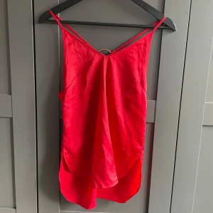 Röd topp från BikBok - Röd topp från Bik Bok med tunna axelband och en dekorativ ringdetalj i ryggen. 