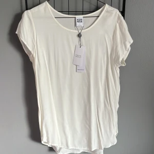 Vit kortärmad topp från Vero Moda - Säljer en stilren vit topp från Vero Moda i storlek S. Den har en rund halsringning och korta ärmar 🥥