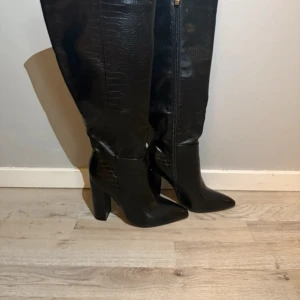 Svarta stövlar med klack - Snygga svarta stövlar i skinn med hög klack och dragkedja på sidan. Perfekta för en stilren look.