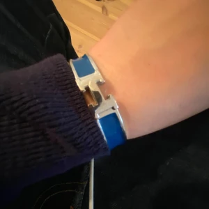 Blått armband med silverdetaljer - Snyggt blått armband med en stilren design och silverdetaljer. Armbandet har en unik låsmekanism som ger det en exklusiv känsla. Perfekt för att ge en färgklick till din outfit.