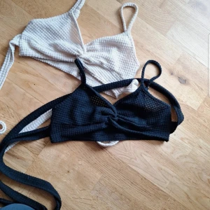 Svart och vit ribbad bikini - Topp å kunna ha till stranden öber sin bikini man knyter banden runt magen fast man kan klippa bort snörena om man vill