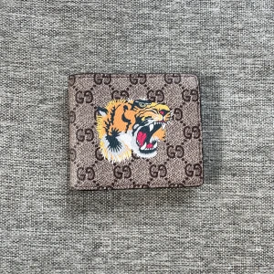 Brun plånbok med tigertryck - Säljer en snygg brun plånbok med ett coolt tigertryck på framsidan. Plånboken har det klassiska GG-mönstret och flera kortfack inuti. Perfekt för att hålla ordning på dina kort och kontanter. Skriv innan ni köper