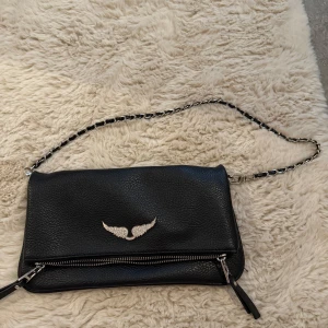 Svart axelväska med kedja  - Snygg svart axelväska i skinn Perfekt för att ge din outfit en edgy touch. används tyvärr inte 