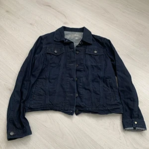 Mörkblå jeansjacka  - Säljer en snygg mörkblå jeansjacka från Gap. Jackan har en klassisk design med knappar framtill och två bröstfickor med knapp. Perfekt för en casual look.
