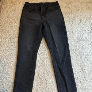 Svarta jeansbyxor - Snygga svarta jeansbyxor med en klassisk design. De har en normal passform och är perfekta för en stilren look. Byxorna har fem fickor och en knappgylf.