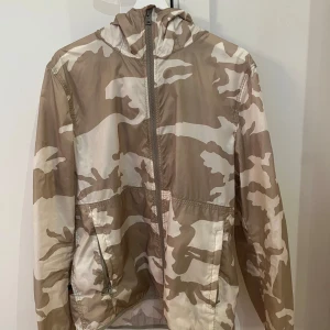 Beige camo vindjacka från Woolrich - Tja ,säljer en snygg beige camouflage vindjacka från Woolrich. Jackan är relativt tunn och passar perfekt nu till våren och sommaren. Passar dig som är 180-193 perfekt.  Använd väldigt lite och är i mycket bra skick. Tags är avklippta men finns kvar. 