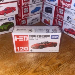 Ferrari SF90 Stradale modellbil från Tomica - Säljer en detaljerad Ferrari SF90 Stradale modellbil i skala 1/62 från Tomica. Förpackningen är röd och vit med bild på bilen. Perfekt för samlare eller bilentusiaster! (Oöppnad)