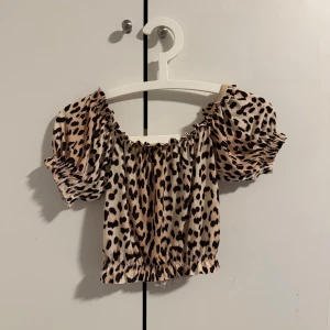 Leopardmönstrad topp från Gina Tricot - Säljer en leopardmönstrad topp från Gina Tricot i storlek XS. Toppen har korta puffärmar och en elastisk kant vid hals och midja för en bekväm passform. Perfekt för att ge din outfit en trendig touch!