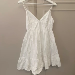 Vit ärmlös klänning - Säljer en söt vit klänning med smala axelband och v-ringning. Klänningen har en volangdetalj längst ner och är perfekt för varma sommardagar 🤍