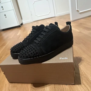 Svarta sneakers med nitar - Snygga svarta sneakers med nitar på tån och sidorna. Skorna har en röd sula med ett unikt mönster. Perfekta för att ge din outfit en edgy touch.