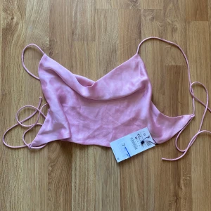 Rosa satinlinnetopp från Zara - Säljer en söt rosa satinlinnetopp från Zara med tunna axelband och knytning i ryggen. Perfekt för en somrig look eller en utekväll. Aldrig använd, prislapp kvar, köpt för 229kr.Hör av er vid frågor💕