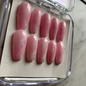 Rosa marmorerade gelenaglar - Naglar med marmorerat mönster. Kommer i en förpackning med tio naglar. Allt som behövs för att sätta fast fem följer med! Storlek:S