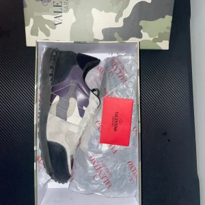 Valentino Rockrunner sneakers i camouflage - Snygga Valentino Rockrunner sneakers med ett coolt camouflagemönster i grått, svart och lila. Perfketa för vår och sommar. Skorna är i näst intill perfekt skick endast få defekter där pytte lite av färgen har skrapats bort. Skorna är i storlek 42.