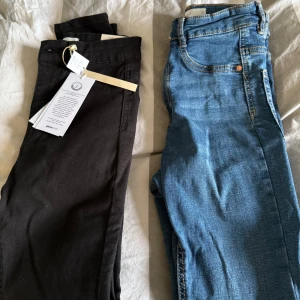 Svarta och blå jeans - Två par jeans från Pieces. Ett par svarta Molly petite high waist jeans och ett par klassiska blå jeans. Båda har en snygg och enkel design med femficksmodell och knappgylf. Perfekta för en stilren look. Nya, de blåa använda några timmar.