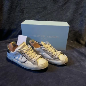 Philippe models  - Snygga Philippe Model sneakers i vitt och grått och marinblå. Skorna är i ett dåligt skick där det är hål på undersidan och i klacken av skorna. Allt og tillkommer i mycket fint skick men skorna är tyvärr ej i det och därav priset. Retale pris ca 3500kr, mitt pris 700kr. Skriv om ni har några frågor eller funderingar ❕