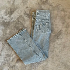 Grå jeans från Gina Tricot - Snygga grå jeans från Gina Tricot med broderad detalj på bakfickan. De har en klassisk femficksdesign och en rak passform. Perfekta för en avslappnad stil.