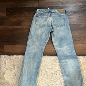 Blå jeans från Weekday/Arrow - Snygga lågmidjade ljusblå jeans från Weekday/ Arrow med klassisk femficksdesign och knappgylf. Perfekta för en avslappnad stil. Tillverkade i bomull med en skön passform. Original priset ligger på 590kr.