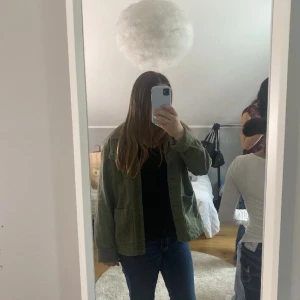 Olivgrön overshirt från H&M - Säljer en olivgrön overshirt från H&M med klassisk krage och knäppning framtill. Jackan har två bröstfickor med lock och två stora fickor nedtill. Perfekt för lager-på-lager och enkel att styla till olika outfits.