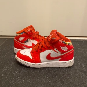 Nike Air Jordans i rött och vitt - Säljer ett par Nike Air Jordans med röd och vit färgkombination. Skorna har röda snören, vit tå och sula samt färgglada detaljer runt ankeln. Klassisk Jordan-logga på plösen och sidan. Perfekta för dig som vill sticka ut med snygga sneakers.