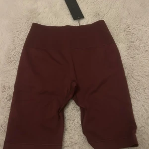 Vinröda prime schrunchfrån Relode - Säljer ett par vinröda träning shorts från Relode. Shortsen är tillverkade i ett stretchigt syntetmaterial och har en diskret rynkdetalj bak. Perfekta för träning eller en sportig look. Prime schrunch modellen, aldrig använda 