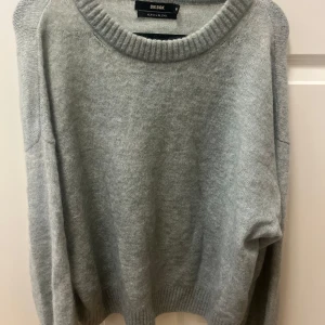 Ljusgrå stickad tröja från Bik Bok - Mysig ljusgrön stickad tröja från Bik Bok i alpackablandning. Tröjan har rund halsringning, långa ärmar och breda ribbade muddar vid ärmslut och nederkant. Perfekt för kyliga dagar! Eller en sen sommar kväll och även en rolig färgglad färg. Endast andvänd 1-2 gånger. Tröjan är i väldigt bra skick.