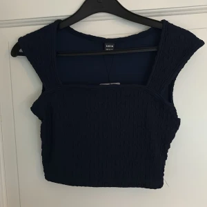 Mörkblå croppad topp från SHEIN - Säljer en mörkblå croppad topp från SHEIN med breda axelband och smockad struktur. Toppen har en fyrkantig urringning, helt oanvänd prislapp kvar