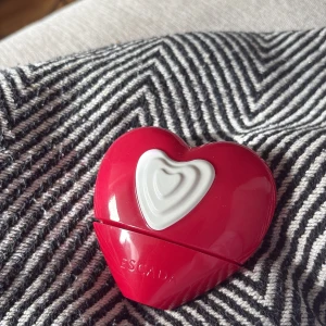 Escada Show Me Love- parfymflaska 50 ml - Säljer en superfin parfym från Escada i en röd hjärtformad flaska med vit detalj framtill. Flaskan rymmer 50 ml och är en riktig eye-catcher på sminkbordet. Perfekt för dig som gillar söta och lekfulla dofter. Ny pris 500kr på Cocopanda