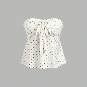 Vit prickig tubtopp med knyt - Säljer en söt vit tubtopp med svarta prickar och knyt framtill. Toppen är axelbandslös och har en lätt utsvängd passform. Perfekt för varma dagar och enkel att styla med jeans eller kjol.