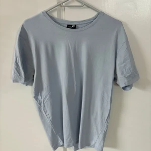 Ljusblå t-shirt från JC - En stilren ljusblå t-shirt från JC i klassisk modell. T-shirten har rund halsringning och korta ärmar. Perfekt basplagg i mjuk bomull som passar till det mesta.