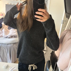 Mörkgrå stickad tröja från Vero Moda - Mysig mörkgrå stickad tröja från Vero Moda. Tröjan har rund halsringning och långa ärmar, perfekt för kyligare dagar. Enkel och stilren design som passar till det mesta, bra skick! 💞