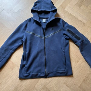 Nike Tech - Mörklblå nike tech. Skick: 7/10✨ Finns pytte små hål vid mitten av tröjan, även ett jätte litet hål i fickan. Den är så liten så att det inte påverkar något.