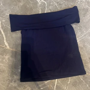 Mörkblå söt topp Kappahl - Säljer en mörkblå söt topp från Kappahl. Toppen  har en enkel och stilren design med bred linning och är tillverkad i ett mjukt och stretchigt material. Perfekt för dig som gillar minimalistisk stil.