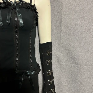 Svarta handskar  med spännen - Säljer  svarta handskar med flera metallspännen och nitar. Bältet har en unik design med flera justerbara remmar och detaljer i silverfärgad metall. Perfekt för att ge en edgy touch till din outfit.