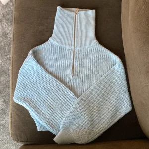 Ljusblå stickad tröja med dragkedja från Primark - Säljer en ljusblå stickad tröja från Primark med hög krage och dragkedja framtill. Tröjan har lång ärm och är ribbstickad vid kragen och ärmsluten. Perfekt för kyliga dagar!