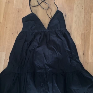 Kort halterneckklänning från Zara - Säljer en svart långklänning med smala axelband och v-ringad halsringning. Klänningen har en luftig passform och volang nertill, perfekt för sommarens alla tillfällen.