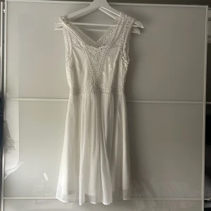 Vit ärmlös klänning med spetsdetaljer - Söt vit klänning med v-ringning och spetsdetaljer . Från Vero Moda. Mycket bra skick. 