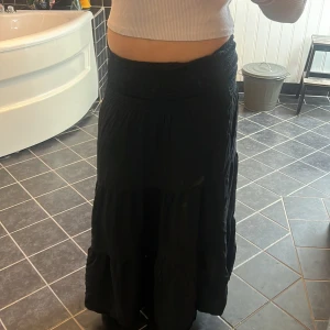 Svart långkjol med resårmidja - Säljer en svart långkjol med bred resår i midjan och lätt volangig nederdel. Kjolen är flowy och passar perfekt till en avslappnad stil. Enkel att matcha med crop tops eller stickade tröjor.